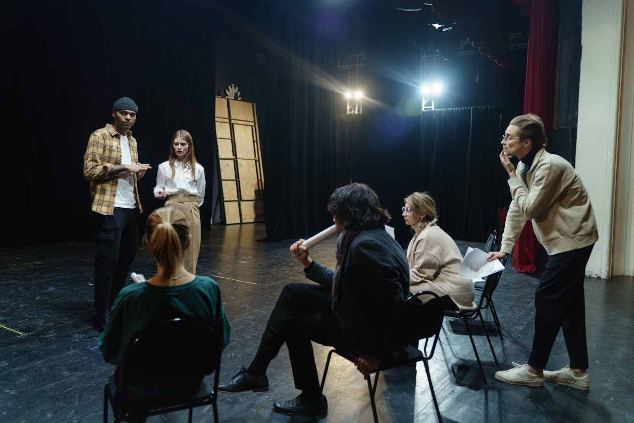 Actors rehearsing on stage with directors guidance in a theater for a live performance.